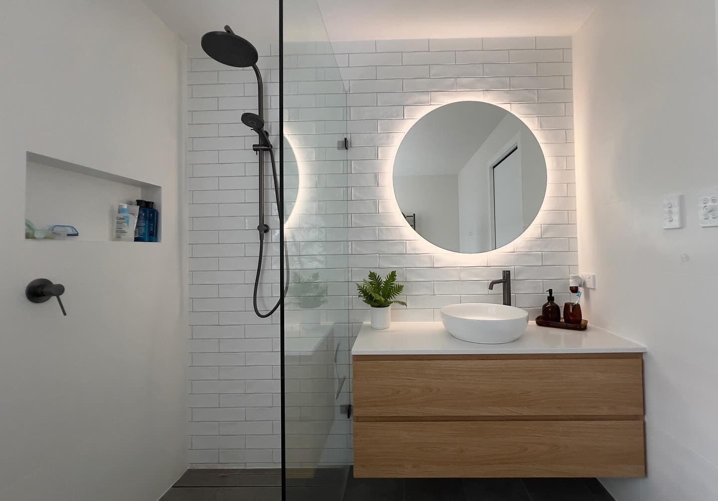Bathroom renovation — backlit round mirror and oak floating vanity